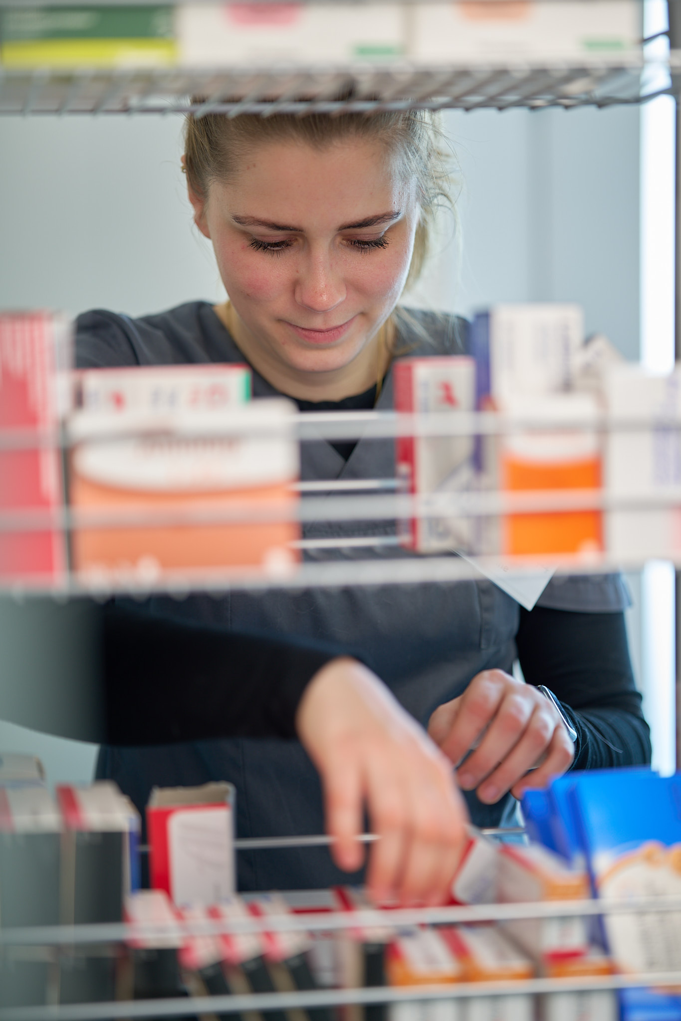 Mitarbeiterin sortiert Medikamente im Praxislager